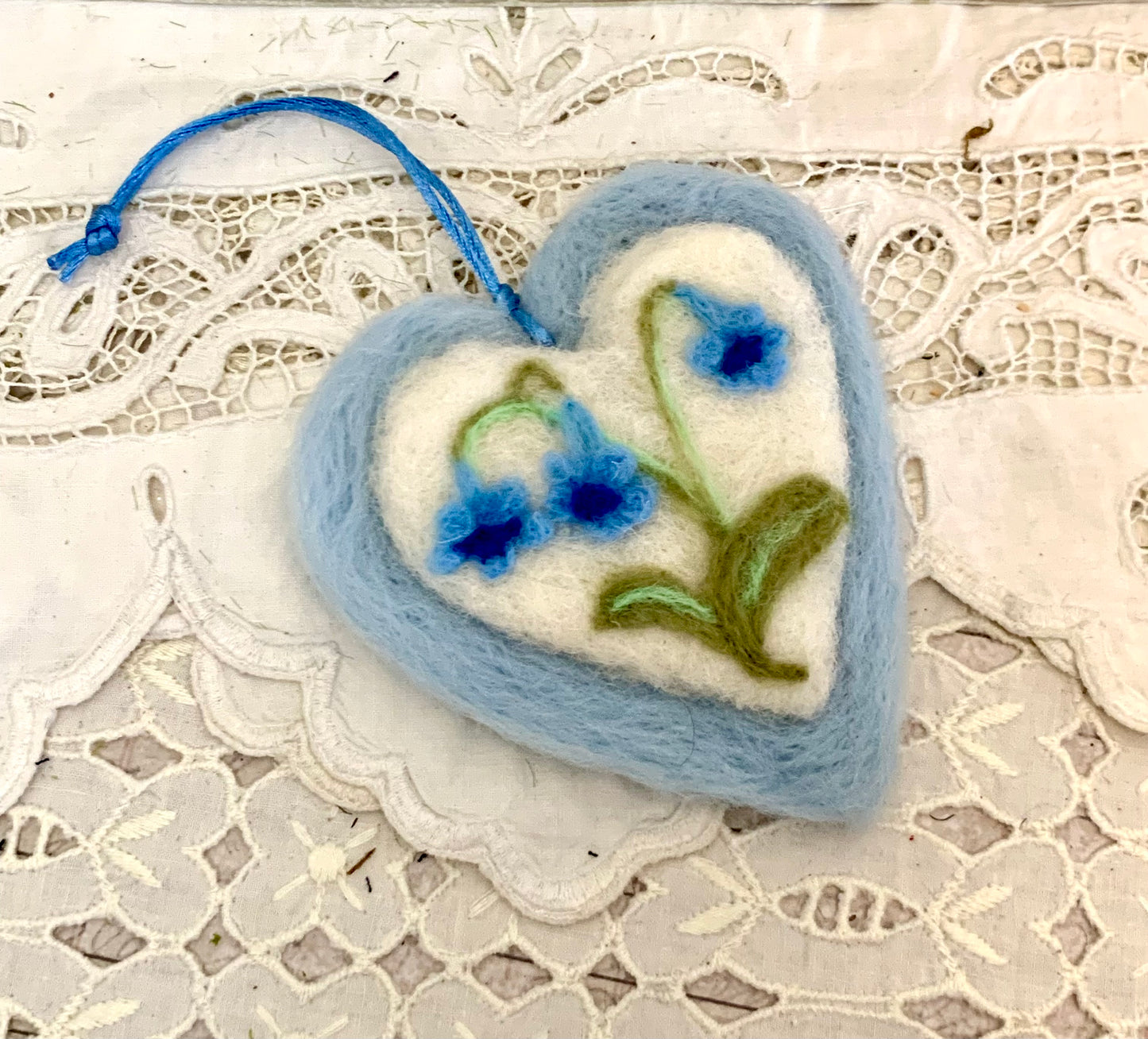 Heart-shaped felted ornament with floral design on a lace background