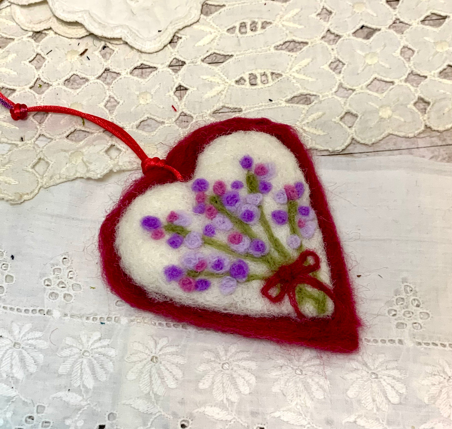 Heart-shaped felt ornament with floral design on a lace background
