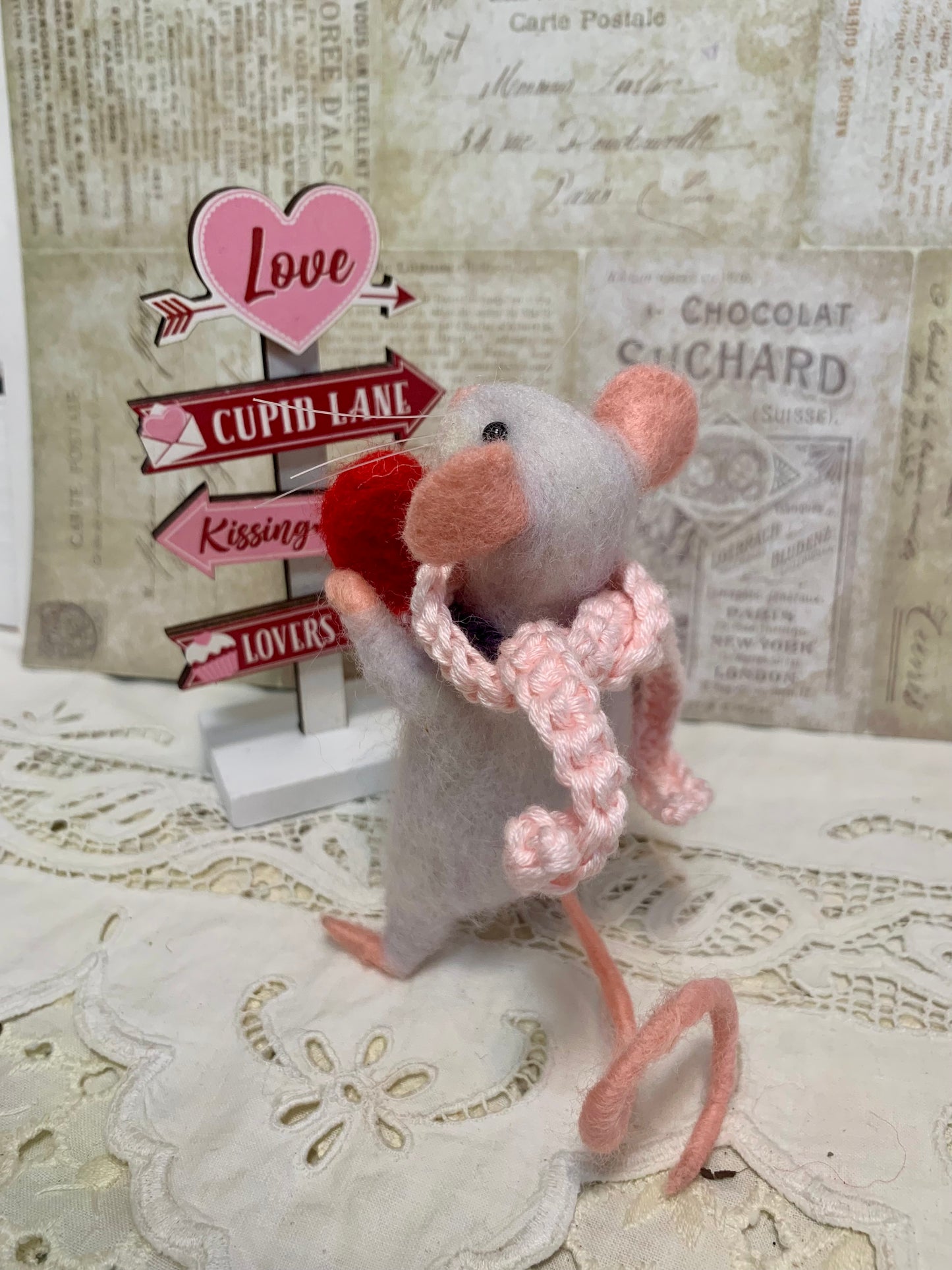 Toy mouse with a pink scarf on a textured surface with vintage-style background