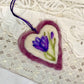 Heart-shaped felted pendant with a purple flower design on a lace background