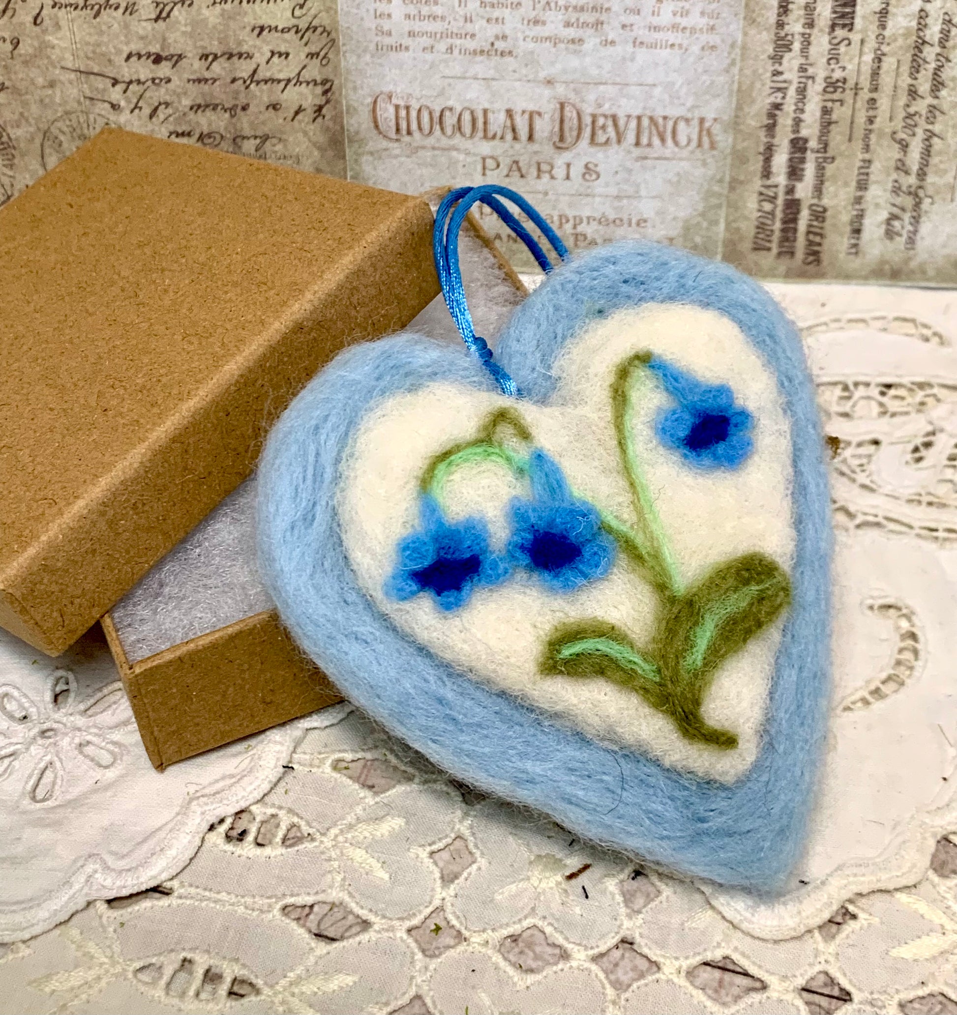 Felted heart ornament with floral design on a textured surface