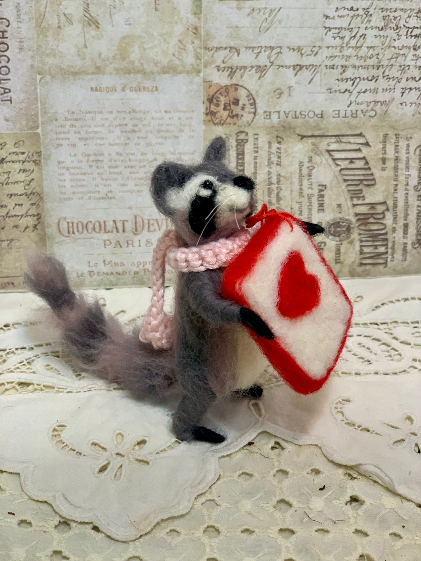 Stuffed animal holding a red and white heart-shaped pillow on a textured surface with vintage text.