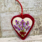 Heart-shaped embroidered ornament with flowers on a textured paper background