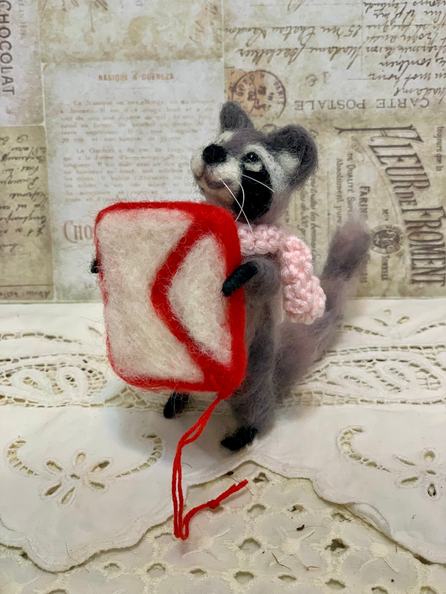 Toy raccoon holding a heart-shaped object on a textured background