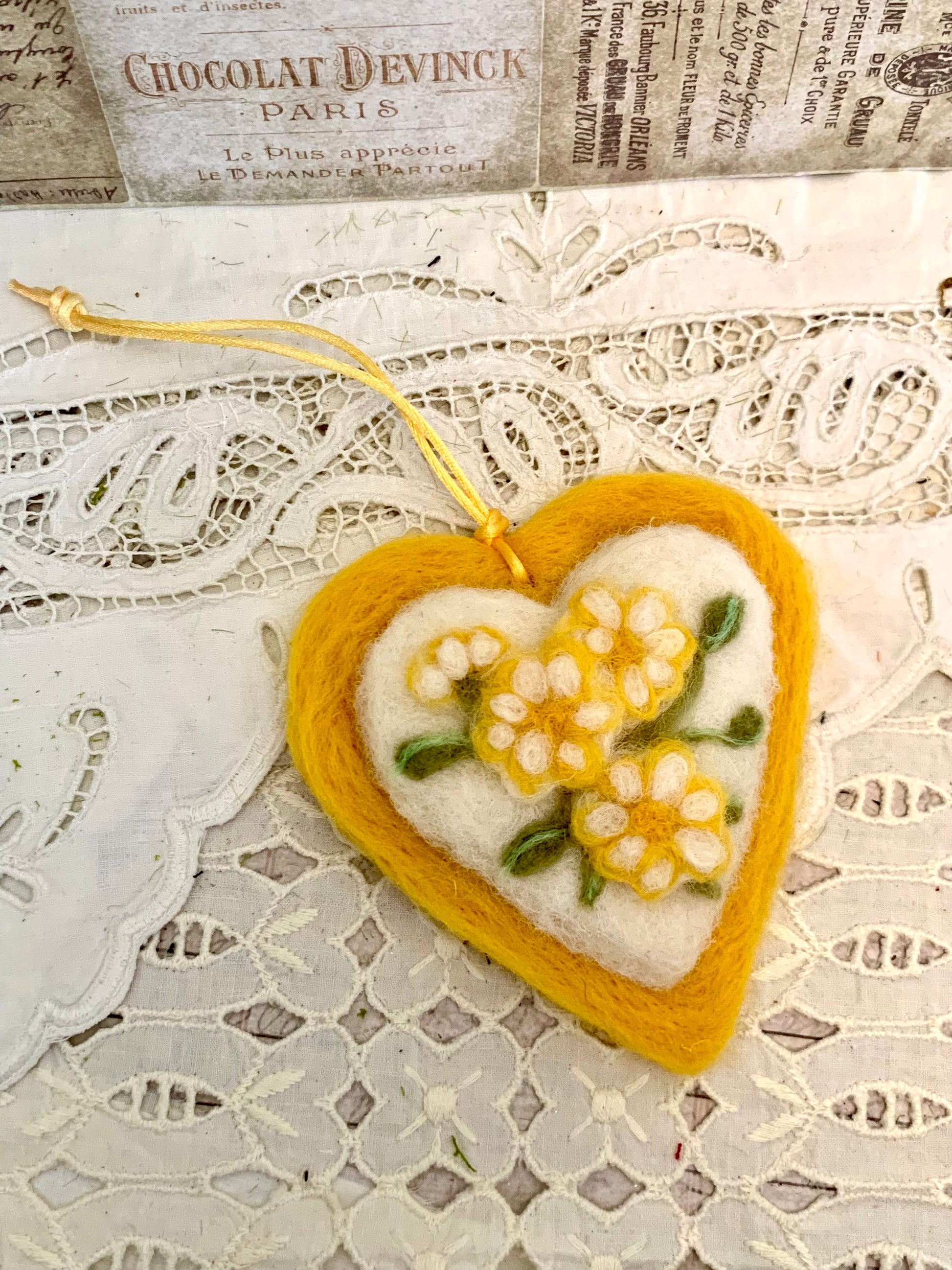 Heart-shaped felt ornament with floral embroidery on a lace background