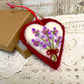 Heart-shaped embroidered ornament with lavender design on a lace surface