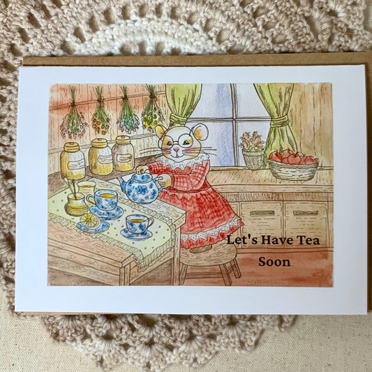 A square greeting card featuring a whimsical watercolor illustration of a hamster in a red dress preparing tea at a table, with the text 'Let's Have Tea Soon' on the bottom right. The card is displayed on a textured beige crochet blanket.