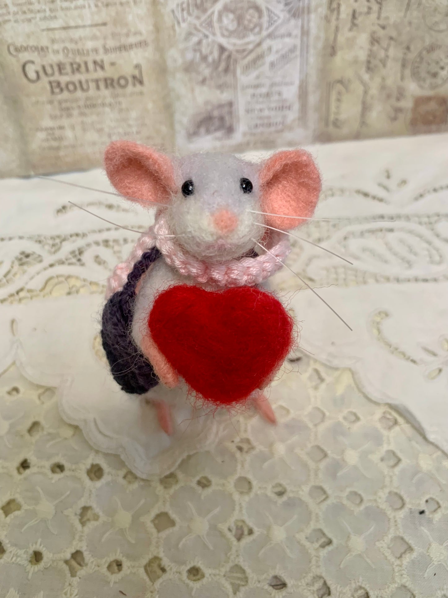 Stuffed mouse toy with a red heart on a lace background