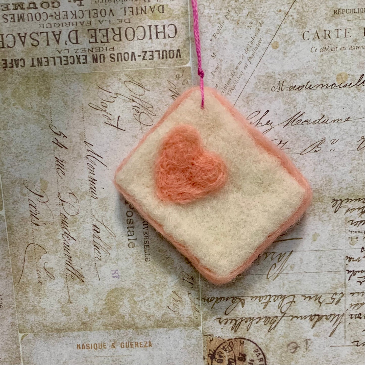 Square piece of fabric with a heart pattern on an old letter background