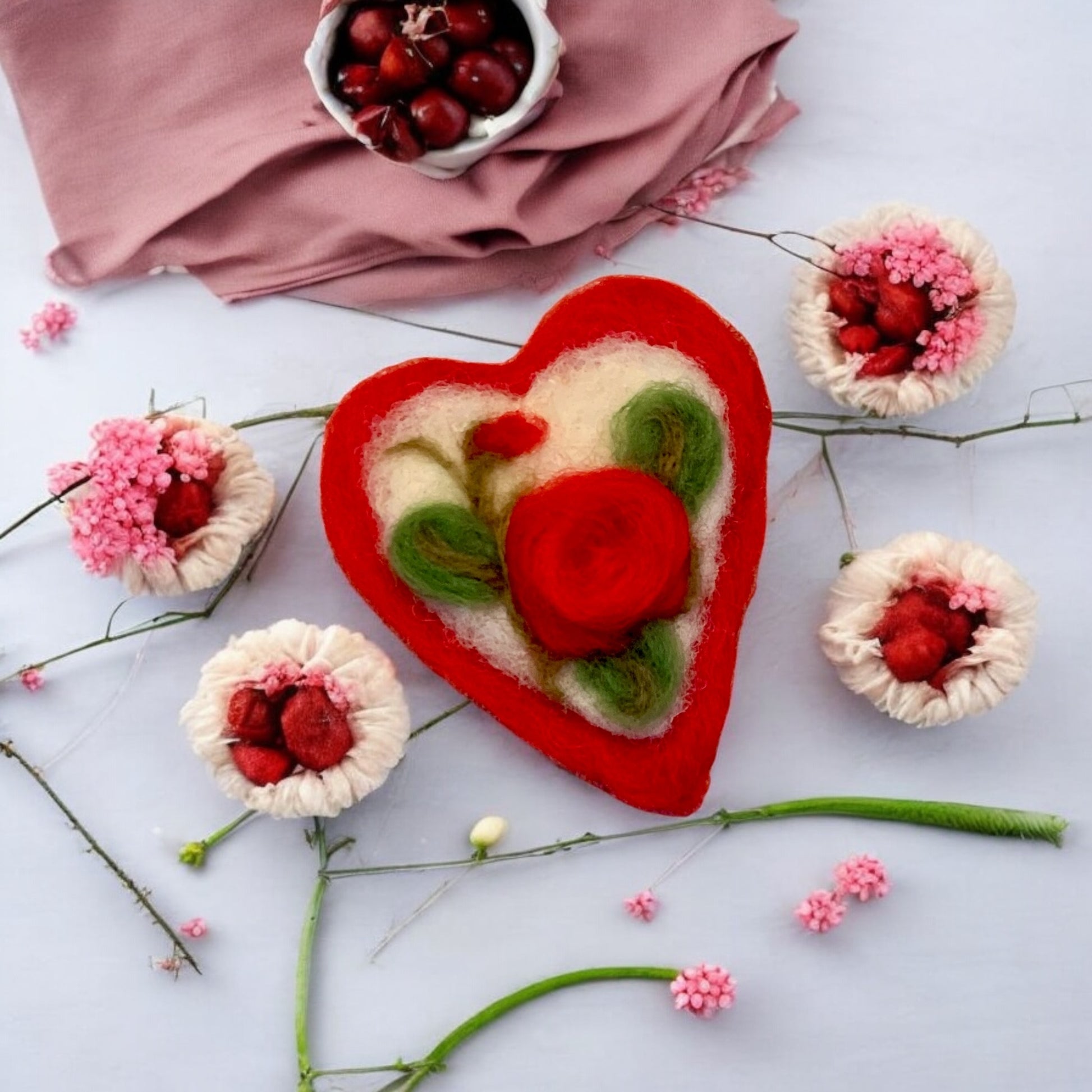 Heart-shaped felted craft with floral design on a light background