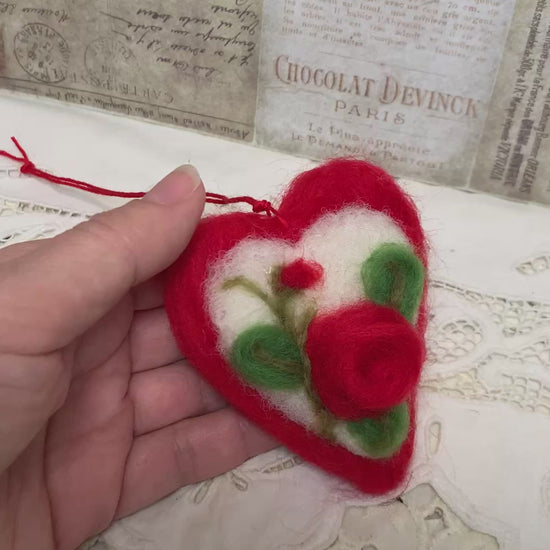 Handmade needle-felted heart is delicately embroidered with a red rose, the timeless symbol of deep love, devotion, and enduring affection.