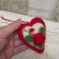 Handmade needle-felted heart is delicately embroidered with a red rose, the timeless symbol of deep love, devotion, and enduring affection.