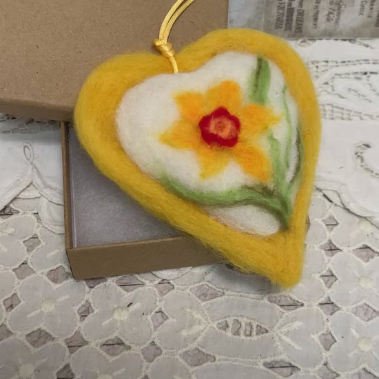 This handmade needle-felted heart is delicately embroidered with a yellow daffodil,