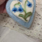 This handmade needle-felted heart is delicately embroidered with a bluebell flower, a timeless symbol of gratitude, humility, and quiet devotion.